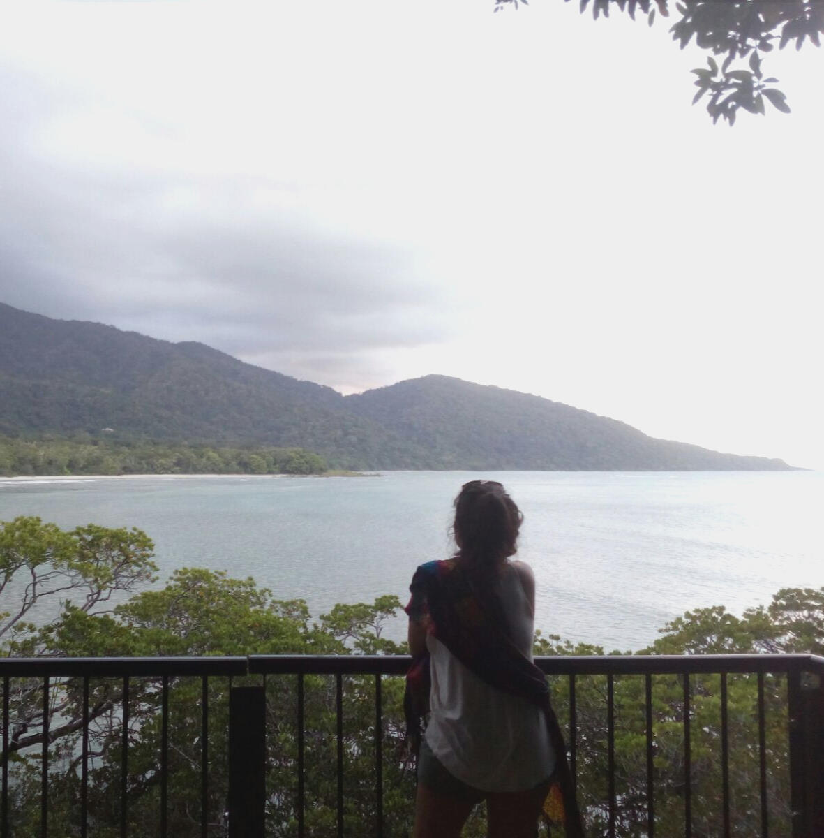 Introspección y propósito en tu camino Flor de espaldas contemplando el mar y las montañas, simbolizando introspección, integración y búsqueda de propósito – Espacio Medrar